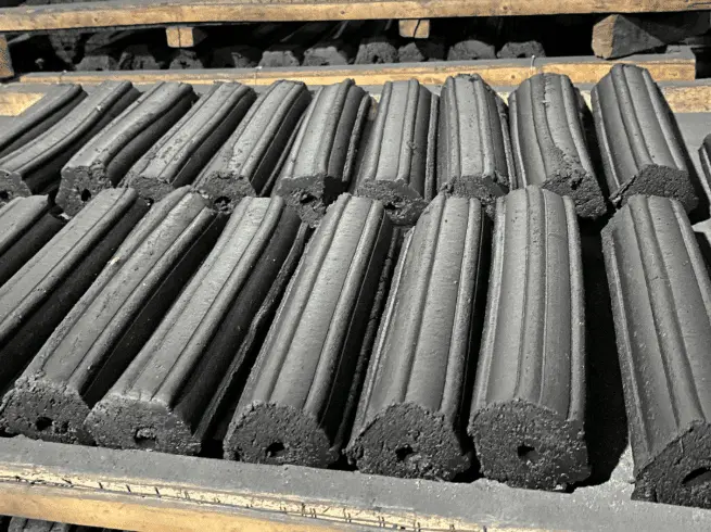 Rows of high-quality hexagonal charcoal briquettes for BBQ and HORECA, showcasing uniform structure and central airflow holes.
